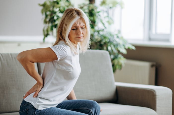 Eine Frau hat Rückenschmerzen, da sie nicht ausreichend Muskeln am Rücken hat durch das zu schnelle Abnehmen.