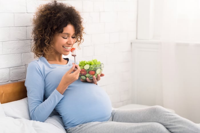 Eine schwangere Frau isst einen Salat.