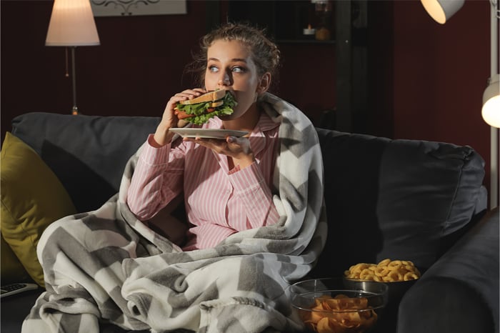 Eine Frau isst betrunken nachts Fast Food und vergisst dabei ihr Kaloriendefizit.