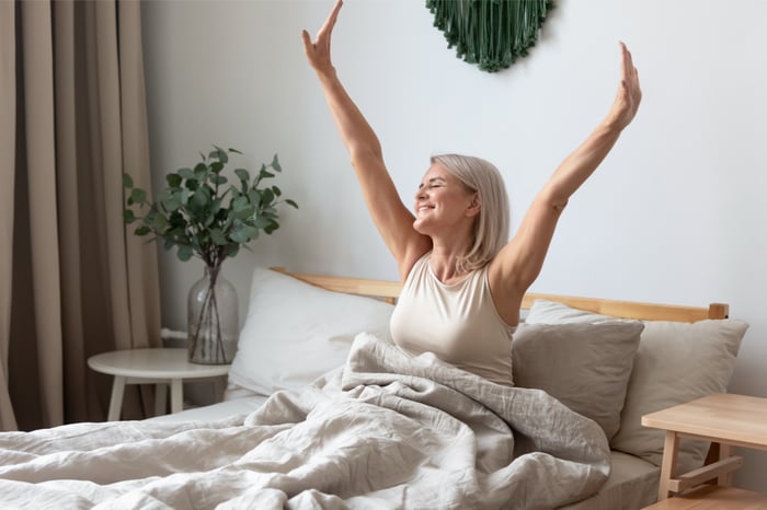 Eine Frau wacht morgens fit auf, da sie durch eine pflanzenbasierte Ernährung ihre Schlafqualität verbessert hat.