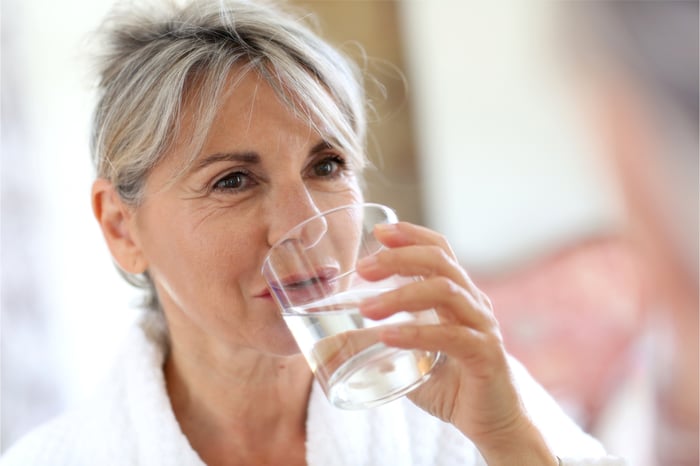 Eine Frau in den Wechseljahren trinkt Wasser.
