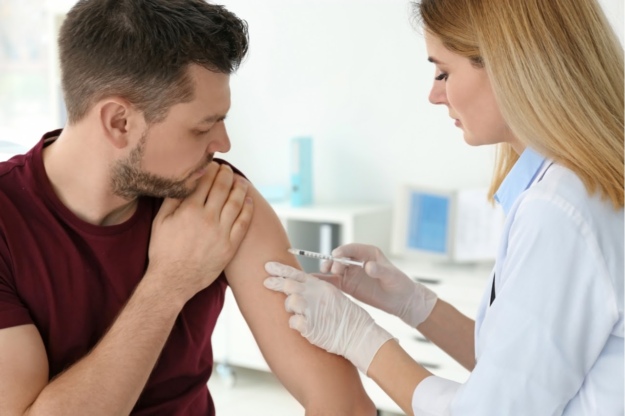 Ärztin führt eine Impfung an einem Patienten durch